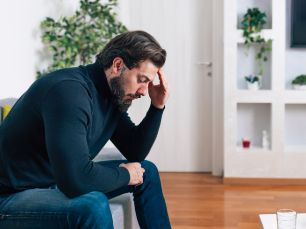 Man sitting and holding head in hand as if stressed